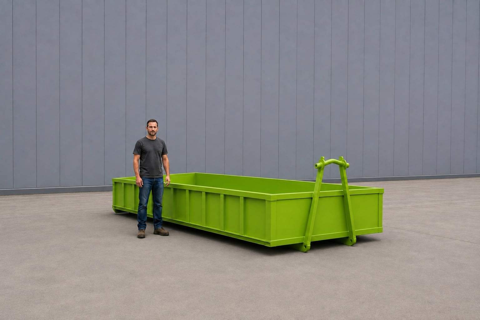 Lime green 10-yard rock box, open-topped with low sides and a raised hook bar at one end, a person standing alongside it for scale