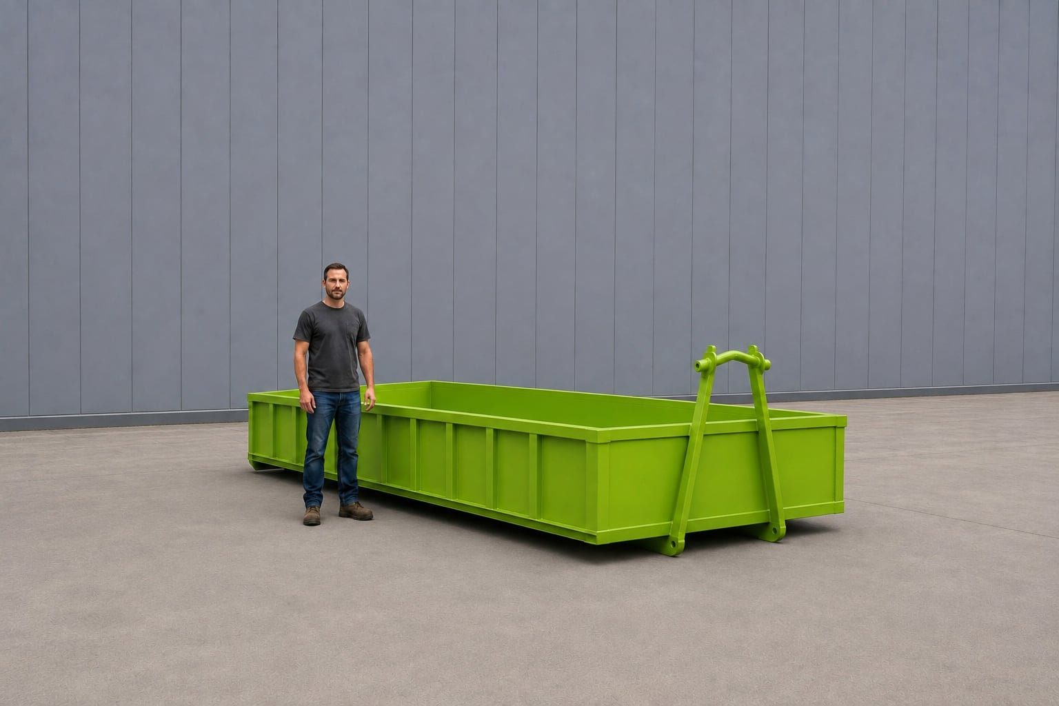 Lime green 10-yard rock box, open-topped with low sides and a raised hook bar at one end, a person standing alongside it for scale