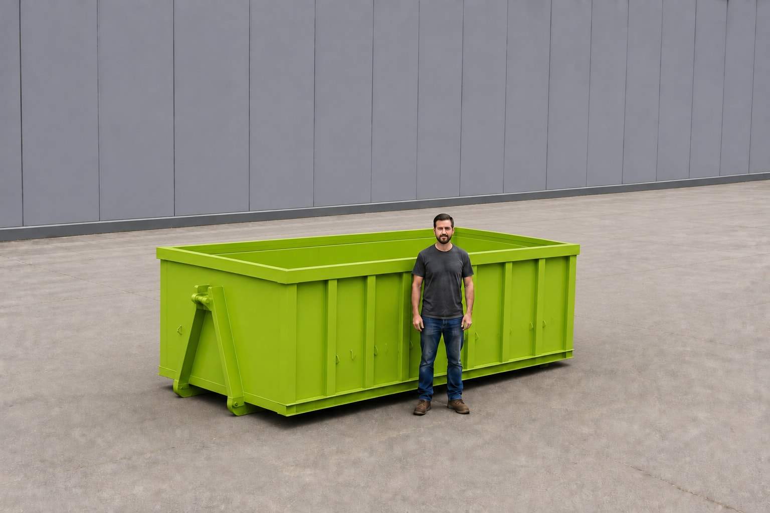 Lime green 15-yard roll-off container photographed side-on against a plain wall, with a person standing beside it to show the height of the sides