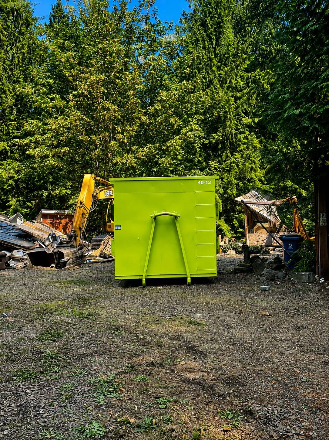 40-yard roll-off container at a demolition job site with an excavator and tear-off debris