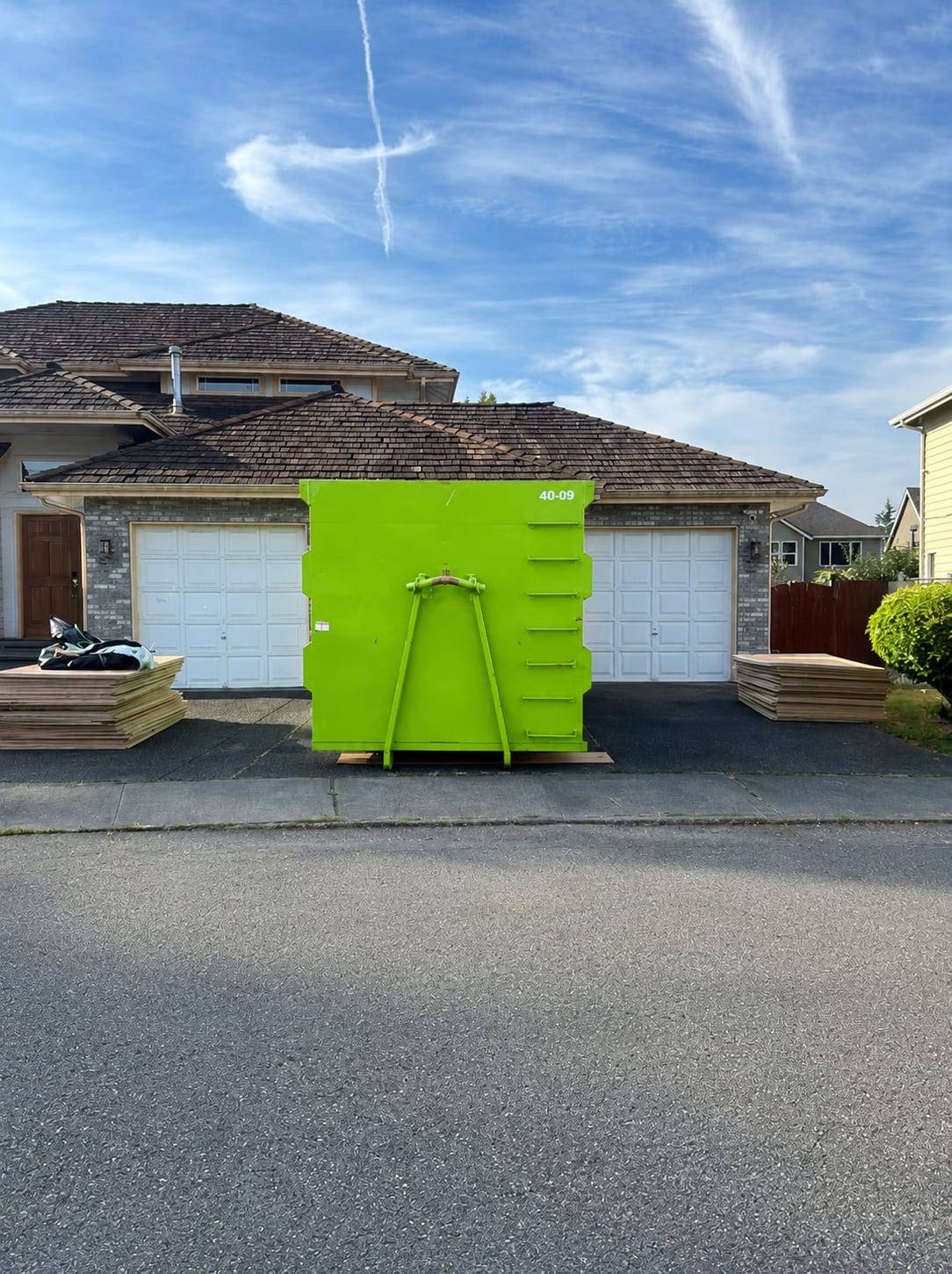 40-yard roll-off container on plywood driveway protection during a cedar shake roof tear-off in Kent