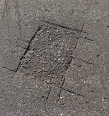 Close-up of a deep crack or permanent gouge in a driveway caused by a heavy roll-off dumpster without wood protection.